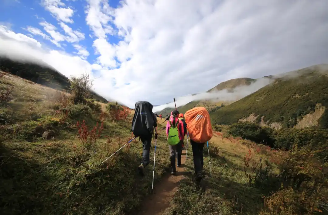 multi day trekking Gongga Mountain hikers crossing alpine meadow